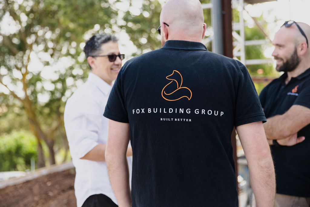 Fox Building Group Team Member Wearing Branded Shirt Talking With Colleagues During A Site Inspection