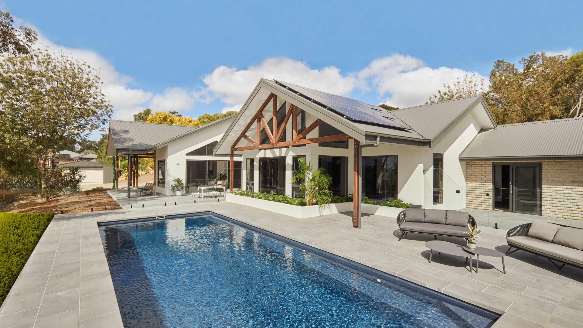 Bespoke Residential Build By Fox Building Group Featuring Striking Exposed Timber Roof Trusses, Extensive Glazing, Solar Panels, And A Tiled Swimming Pool
