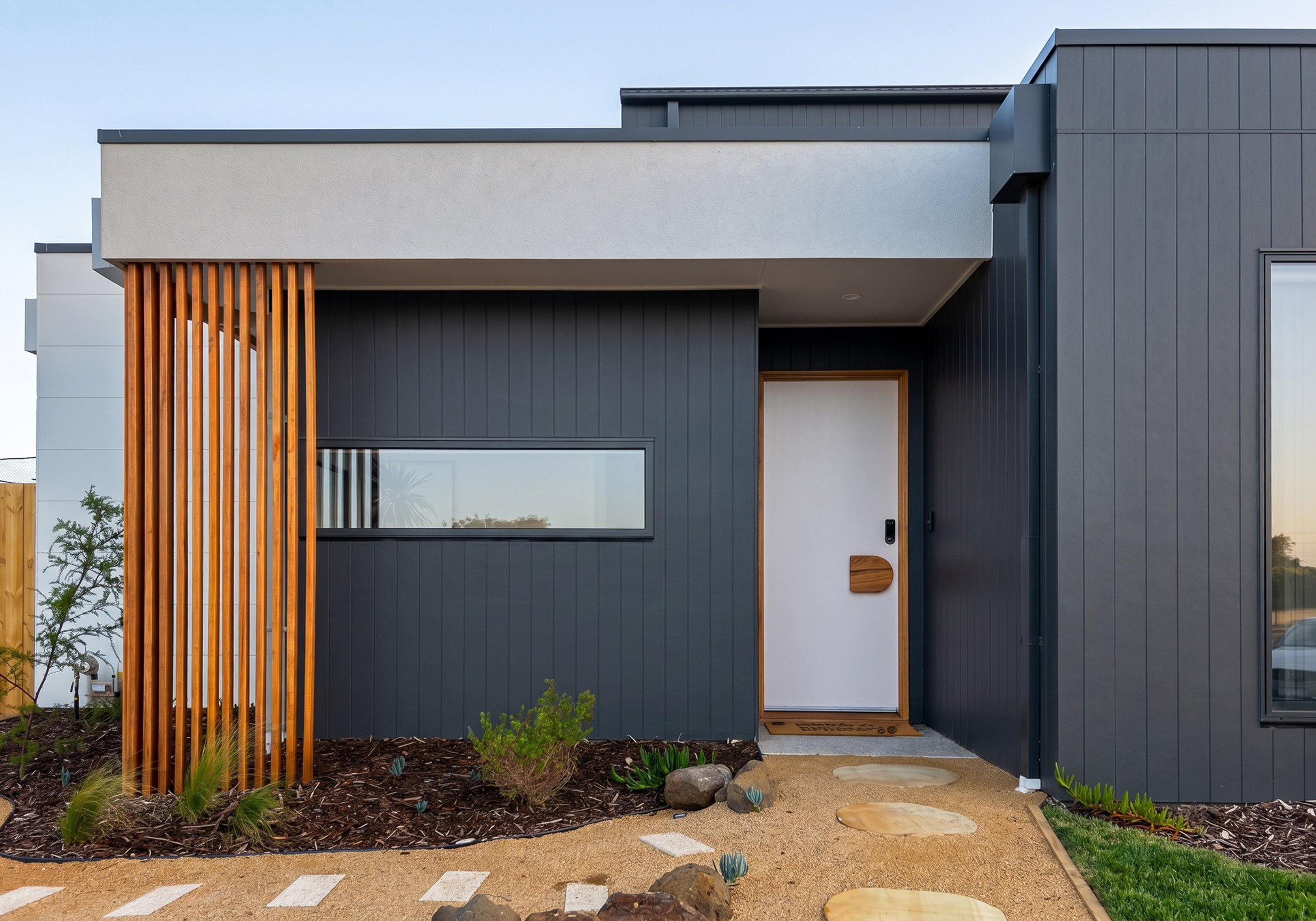 Custom Home Builder Torquay Project Showing Dark Cladding Facade With Timber Slat Entry Screen At Dusk