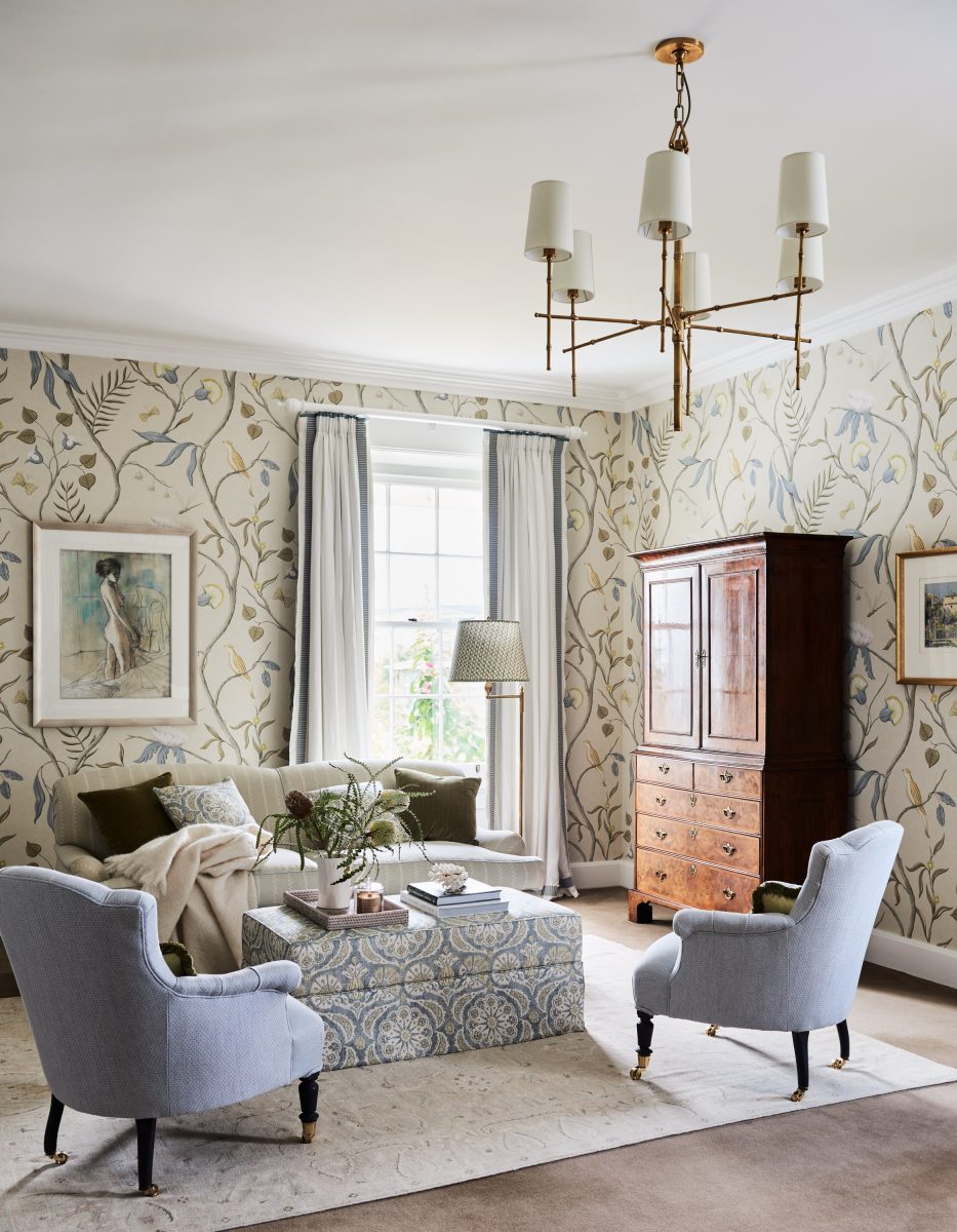 A Grand Bedroom Featuring Blue And Cream Floral Lewis &Amp; Wood Wallpaper, A Canopy Bed With A Gold Headboard, Two Light Blue Armchairs, And A Large Brass Chandelier.