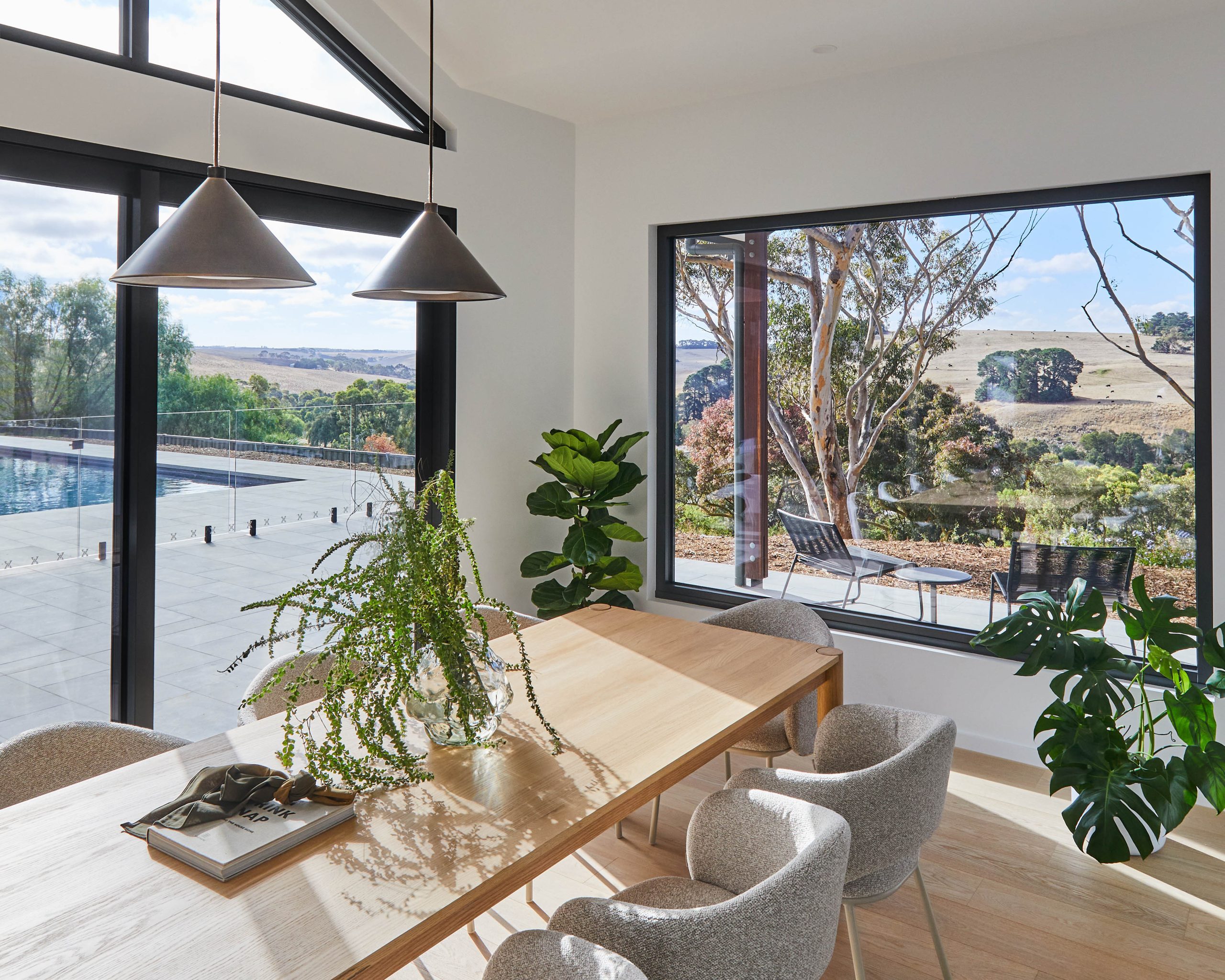 Dining Table With Pendant Lighting Framed By Views Of The Pool And Paddocks