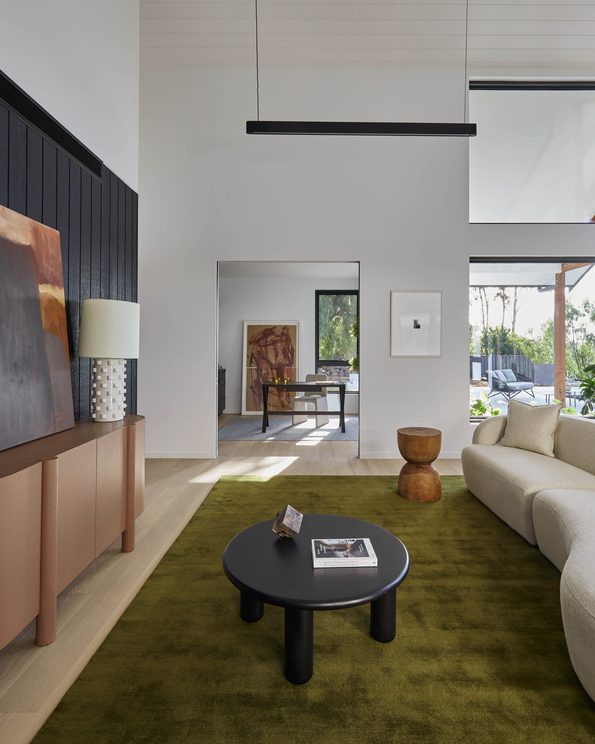 Curved Bouclé Sofa Beside A Hand-Forged Black Coffee Table In The Living Room