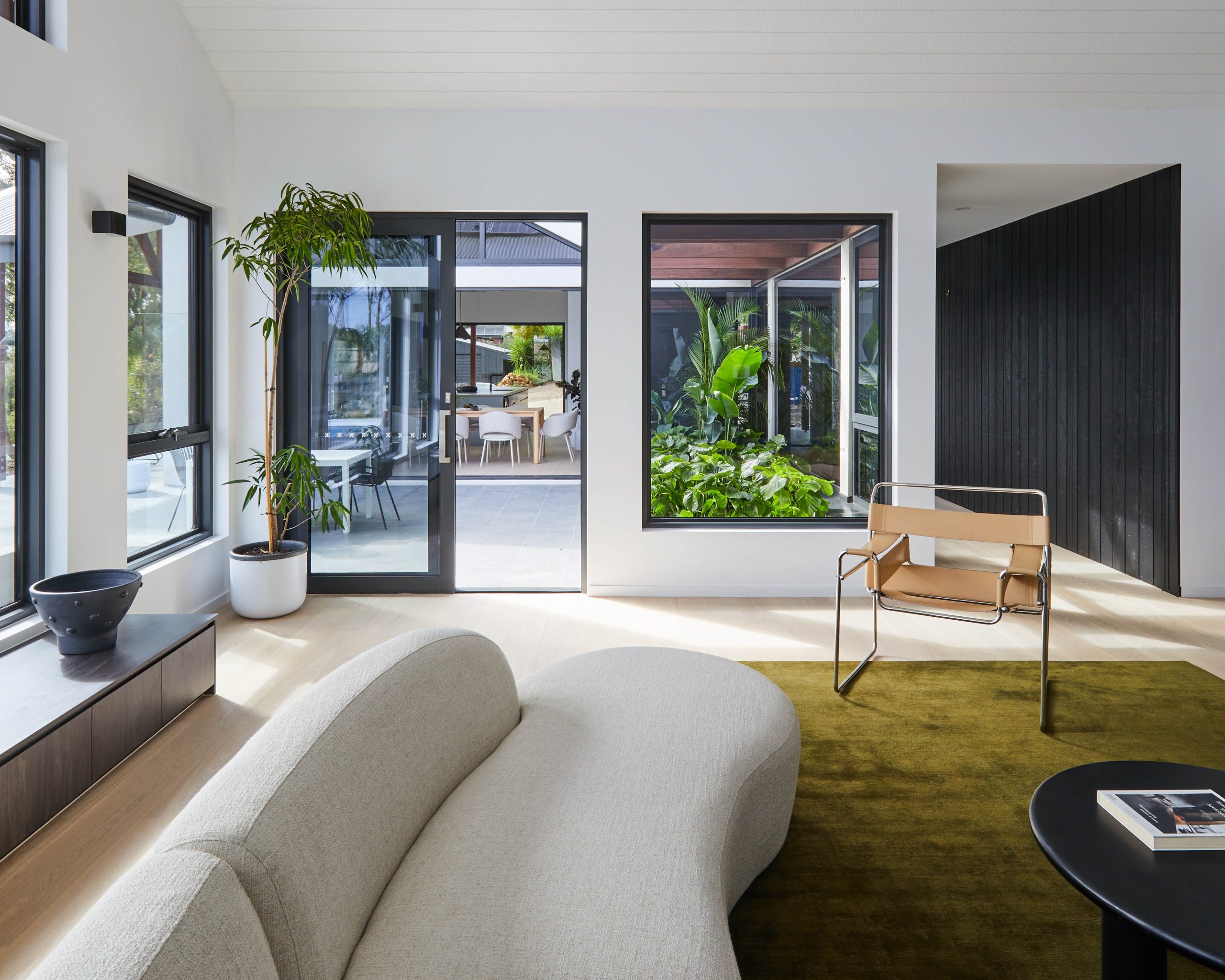Living Room Dark-Stained Joinery Wall With Artwork And Courtyard Glazing