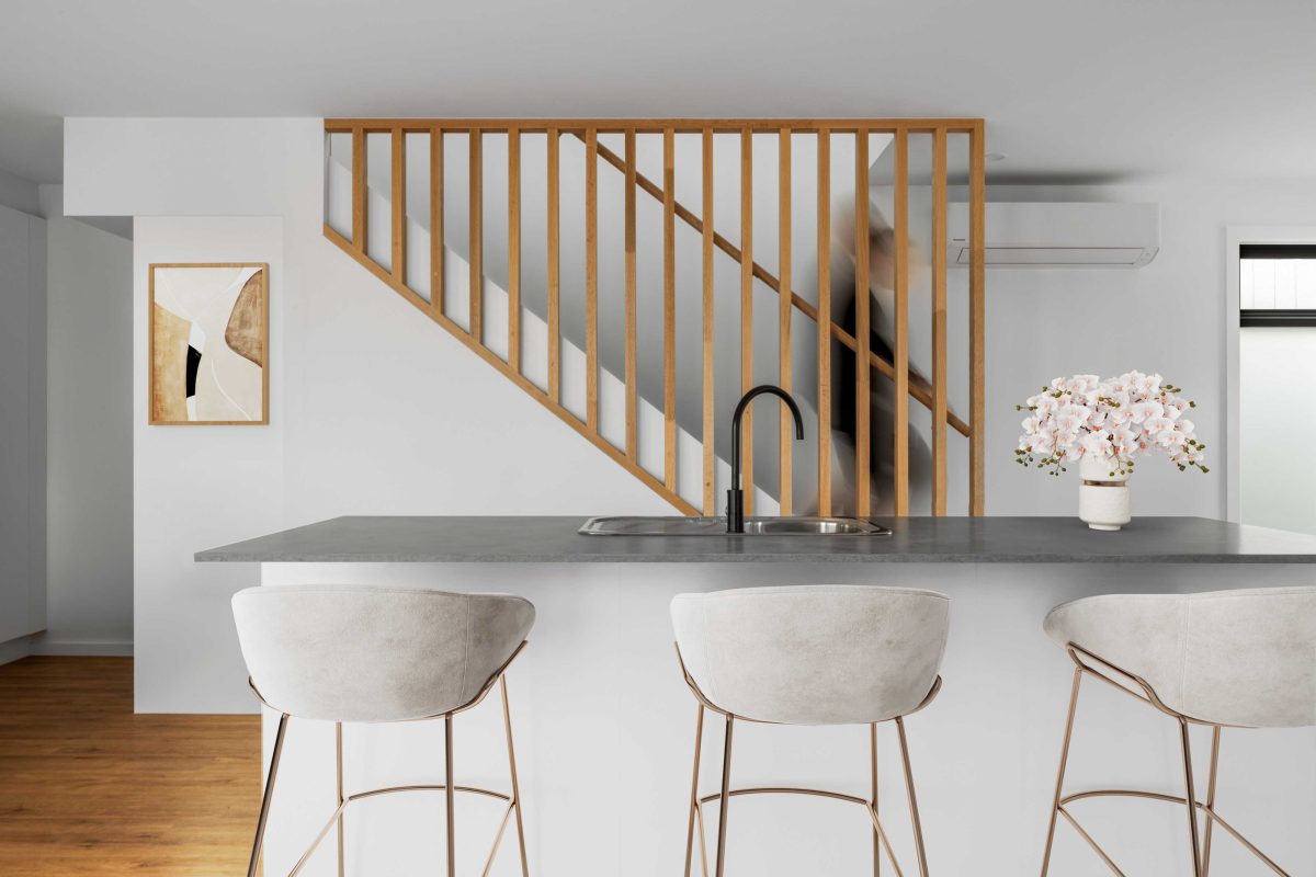Townhouse Development South Geelong – Kitchen With Waterfall-Edge Stone Island Bench, Black Tapware And Timber-Slat Staircase