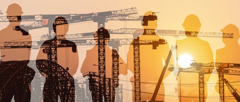 Silhouettes Of Construction Workers And Cranes Against A Sunset Sky, Representing The Resilience And Strategic Planning Required For The 2026 Australian Construction Industry During A Global Energy Shock.
