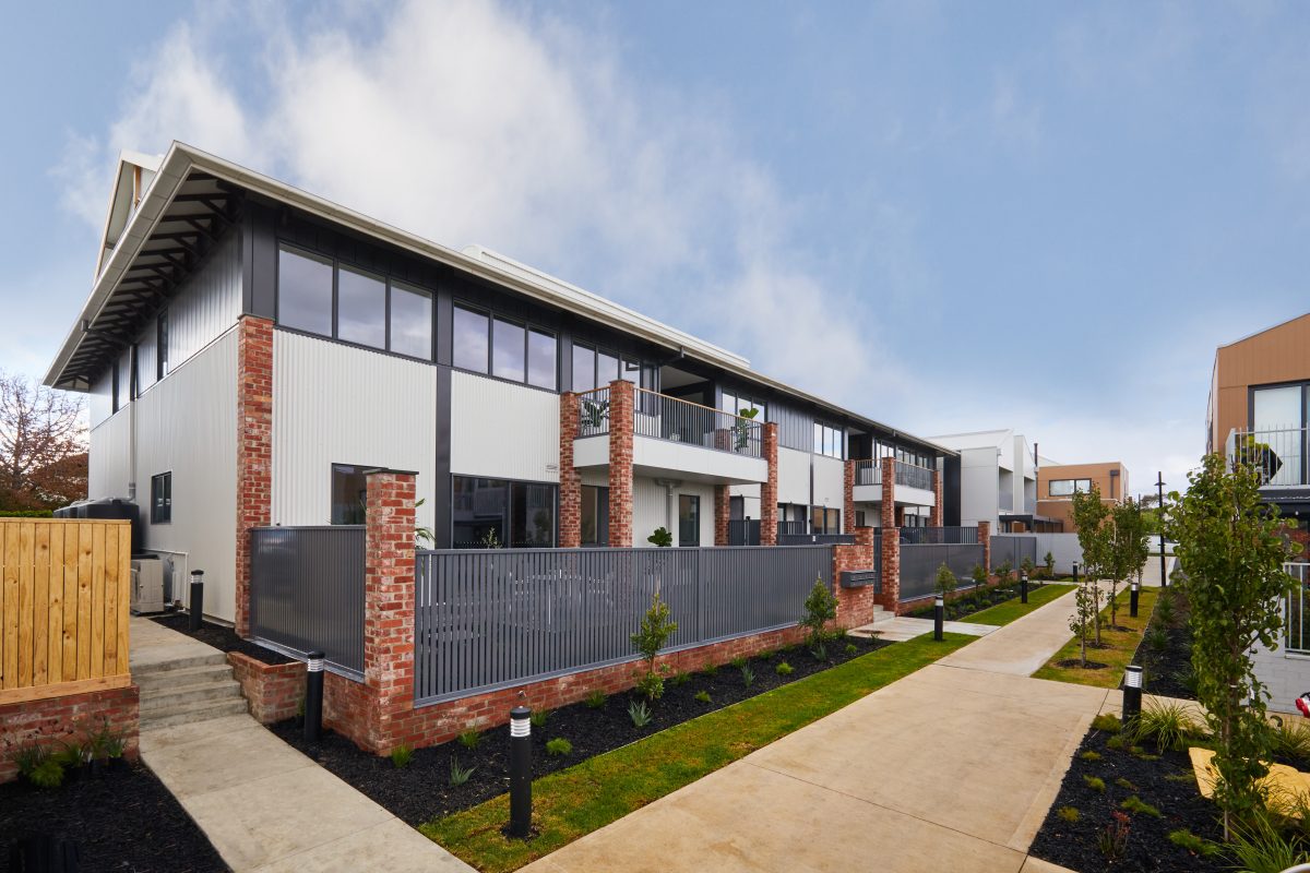 Converted Warehouse Apartments In South Geelong With Recycled Brick Piers Supporting First-Floor Steel Balconies Alongside A Paved Path.
