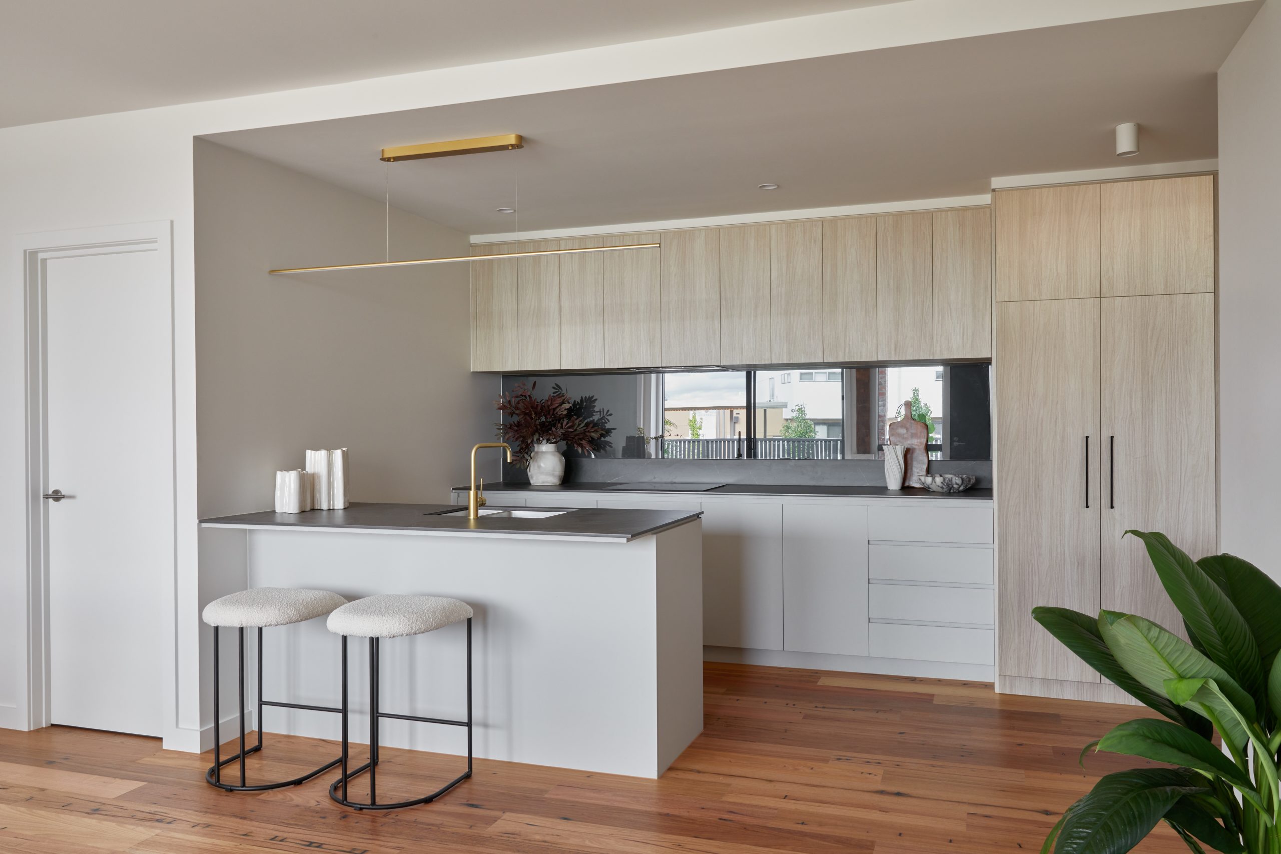 Modern Kitchen Featuring Refined Timber Cabinetry, Stone Island, And Brass Fixtures, Contrasting With Heritage Hardwood Flooring.