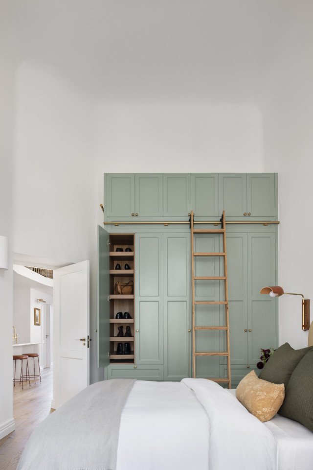 Floor-To-Ceiling Sage Green Wardrobe With A Rolling Ladder In The Primary Bedroom Of The Award-Winning Carlton Renovation By Fox Building Group.