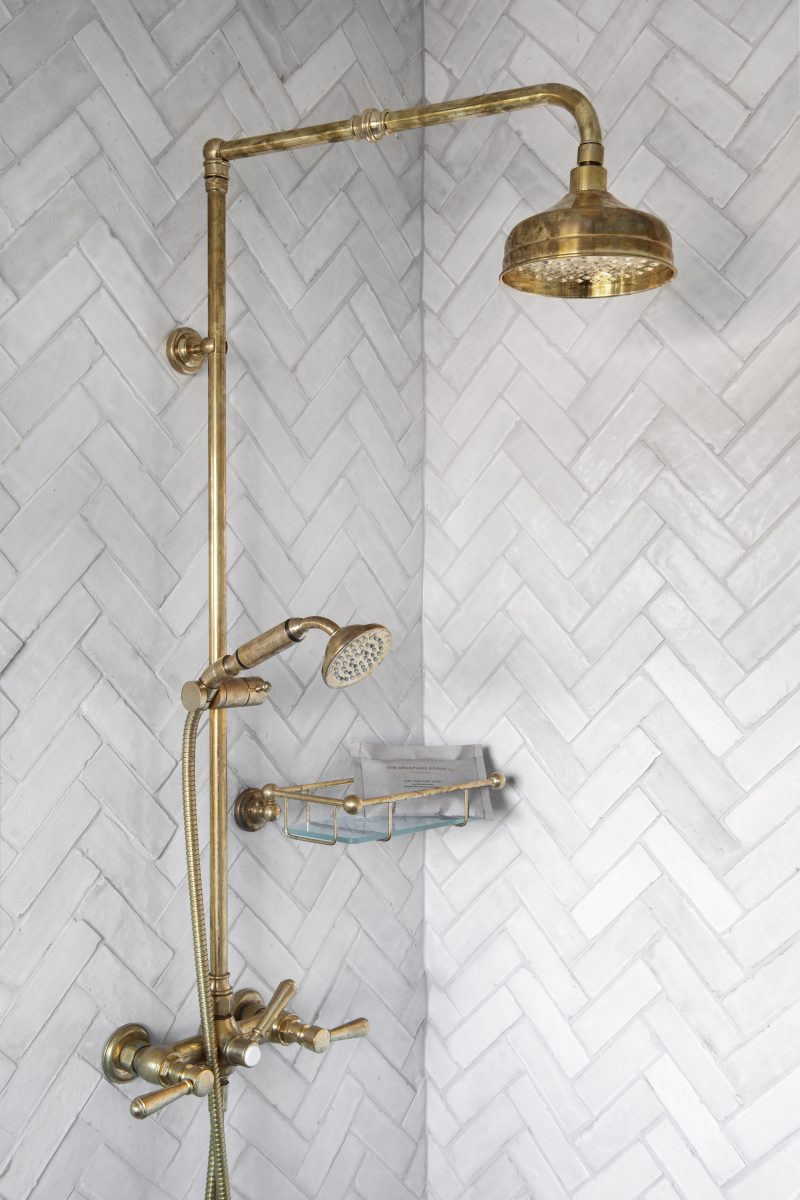 Antique Brass Exposed Shower Fittings Against White Herringbone Tiling In The Bathroom Of The Award-Winning Carlton Renovation By Fox Building Group.