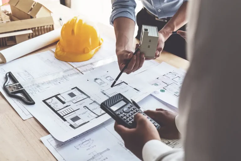 Architect And Quantity Surveyor Reviewing A Commercial Cost Plan Against Building Plans